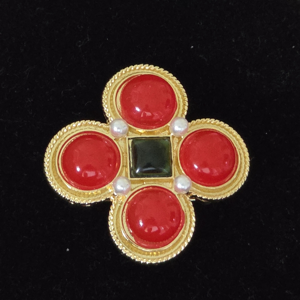 This is a gold-tone metal jeweled brooch with round red and square green resin